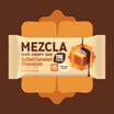 MEZCLA Puff-Crispy Bar in Salted Caramel Chocolate flavor with cream wrapper showing 11g protein, 170 calories, and caramel dripping illustration on orange decorative background