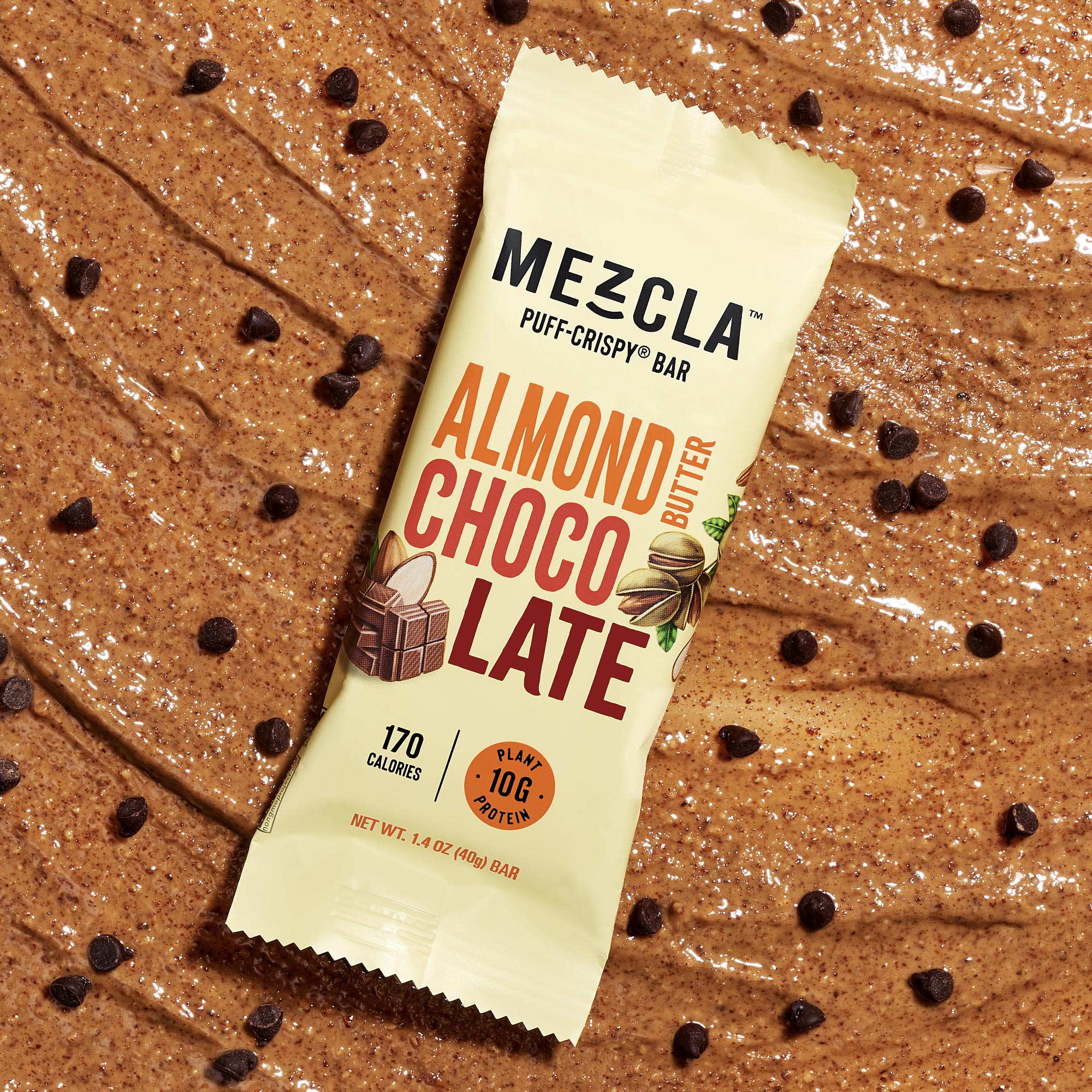 Mezcla Almond Butter Chocolate puff-crispy protein bar package on wooden surface with scattered chocolate chips and flour