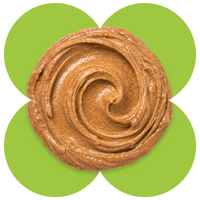 Swirled almond butter with glossy, creamy texture displayed on a green flower-shaped background