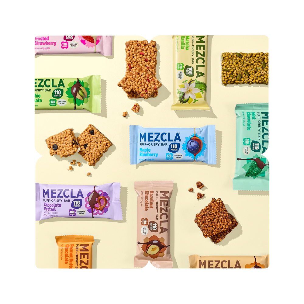 Assorted Mezcla puff-crispy protein bars in colorful packaging including Frosted Strawberry, Apple Blueberry, Chocolate Pretzel, and other flavors with scattered granola pieces