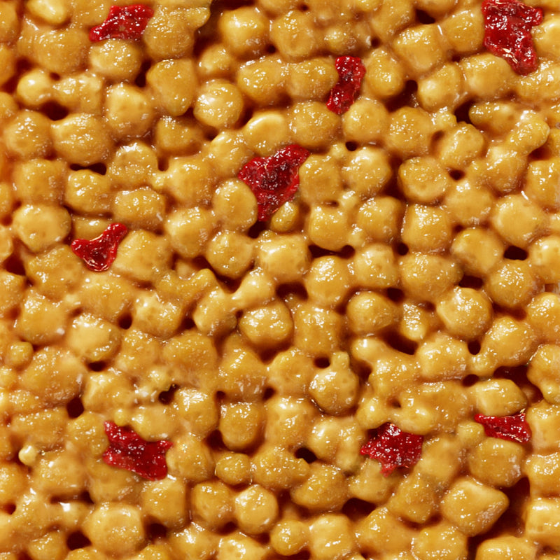 Golden caramel-coated cereal pieces mixed with red dried cranberries or cherries in a close-up view