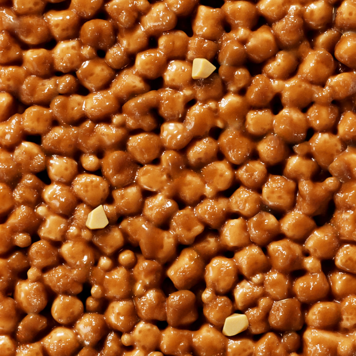 Glazed caramelized walnuts with honey coating and scattered almond slivers, close-up view showing glossy amber texture