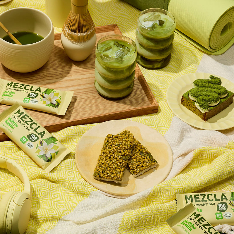 Matcha-themed spread with MEZCLA crispy bars, green tea drinks, desserts and yoga mat on yellow patterned fabric