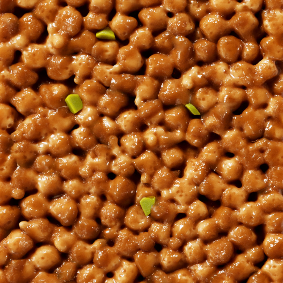 Glazed walnuts with green garnish pieces, close-up view showing glossy caramelized coating on nuts