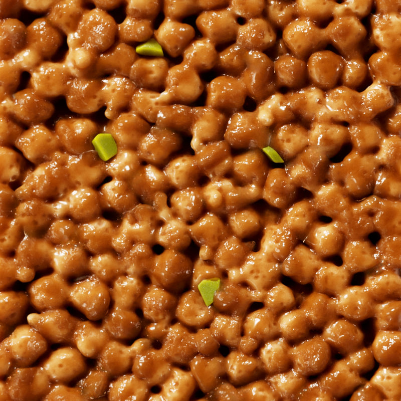 Glazed walnuts with green garnish pieces, close-up view showing glossy caramelized coating on nuts