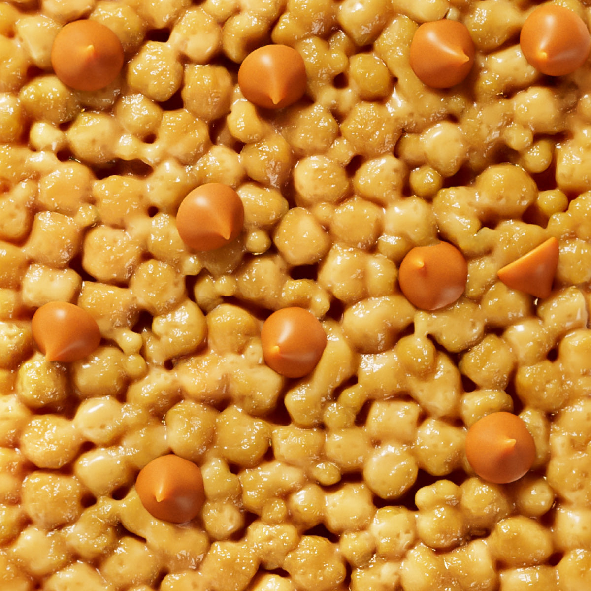 Mixed nuts and cereal pieces in golden honey coating with orange butterscotch chips scattered throughout