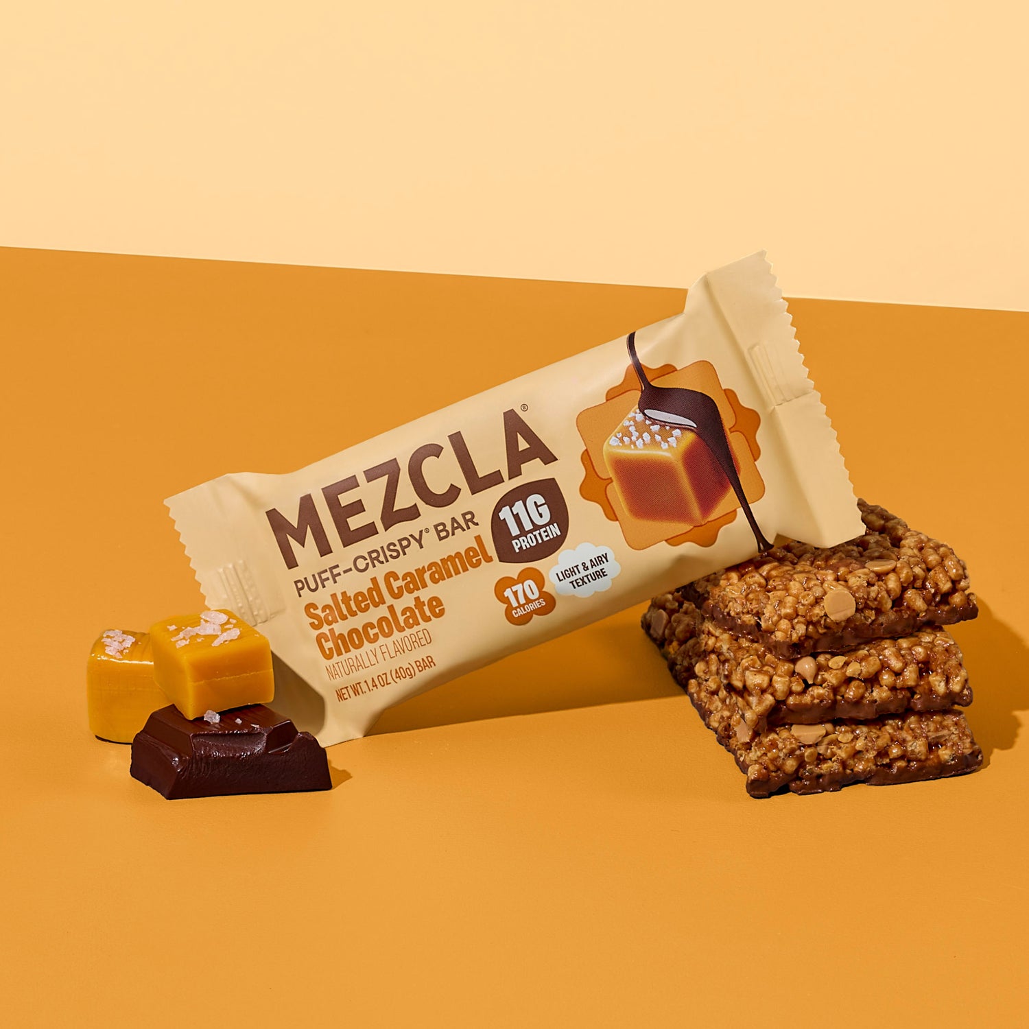 MEZCLA Puff-Crispy Bar in Salted Caramel Chocolate flavor on orange background with caramel and chocolate pieces, showing 11g protein and 170 calories.
