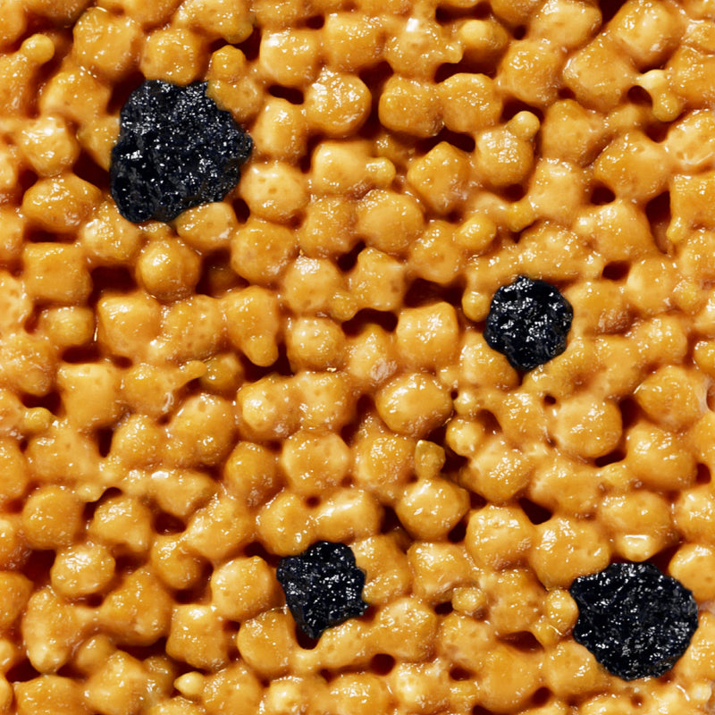 Golden crispy rice cereal with dark raisins scattered throughout, appearing glossy and caramelized
